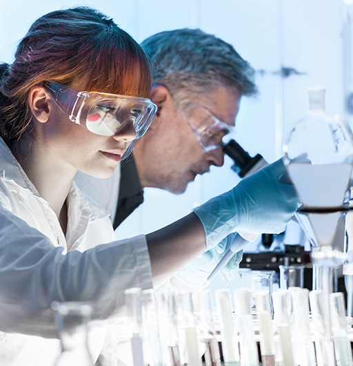 Zwei Wissenschaftler im Forschungslabor mit Schutzbrille und Mikroskop